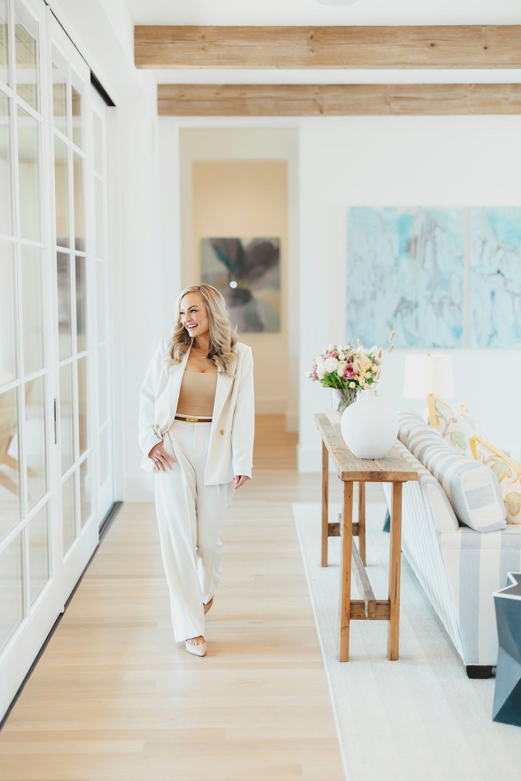Kaitlin Lovern, North Dallas REALTOR, in a cream suit in a home hallway, serving McKinney, TX