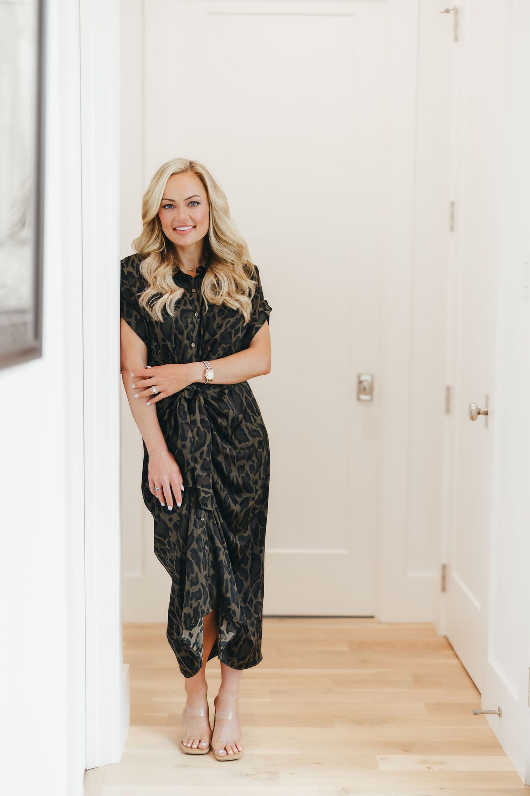 Kaitlin Lovern, North Dallas REALTOR, in a leopard-print dress at a doorway, serving Frisco, TX
