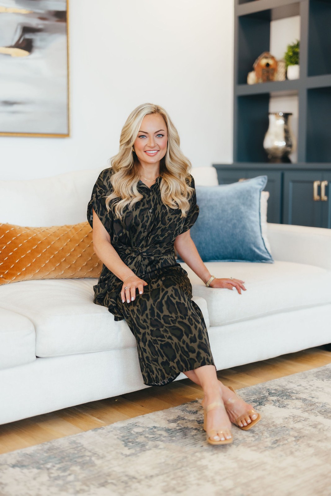 Kaitlin Lovern, North Dallas REALTOR, in a leopard-print dress seated on a sofa