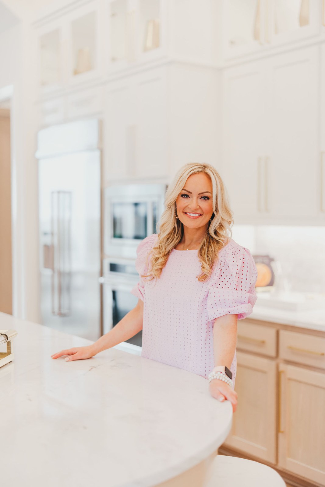 Kaitlin Lovern, North Dallas REALTOR, in a lilac blouse at a kitchen counter, serving Allen, TX