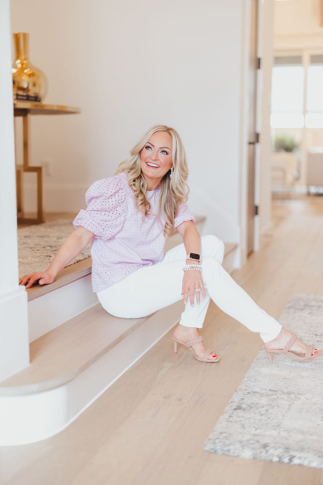 Kaitlin Lovern, North Dallas REALTOR, in a lilac blouse on a staircase