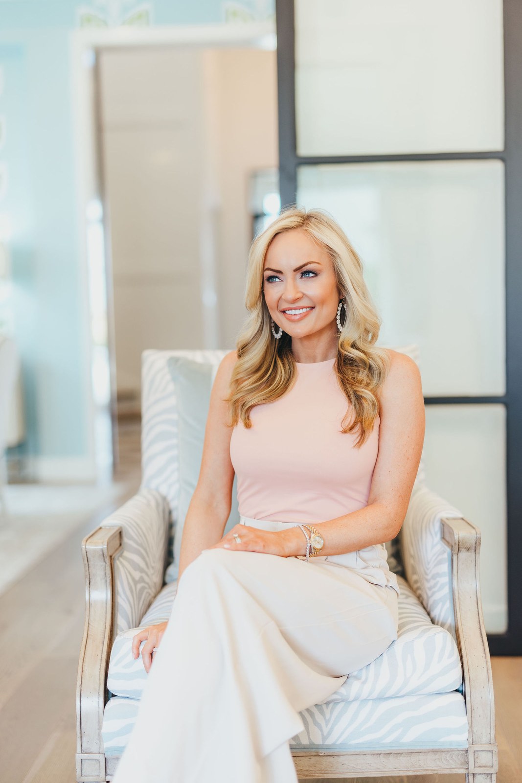 Kaitlin Lovern, North Dallas REALTOR, in a pink top seated in a chair