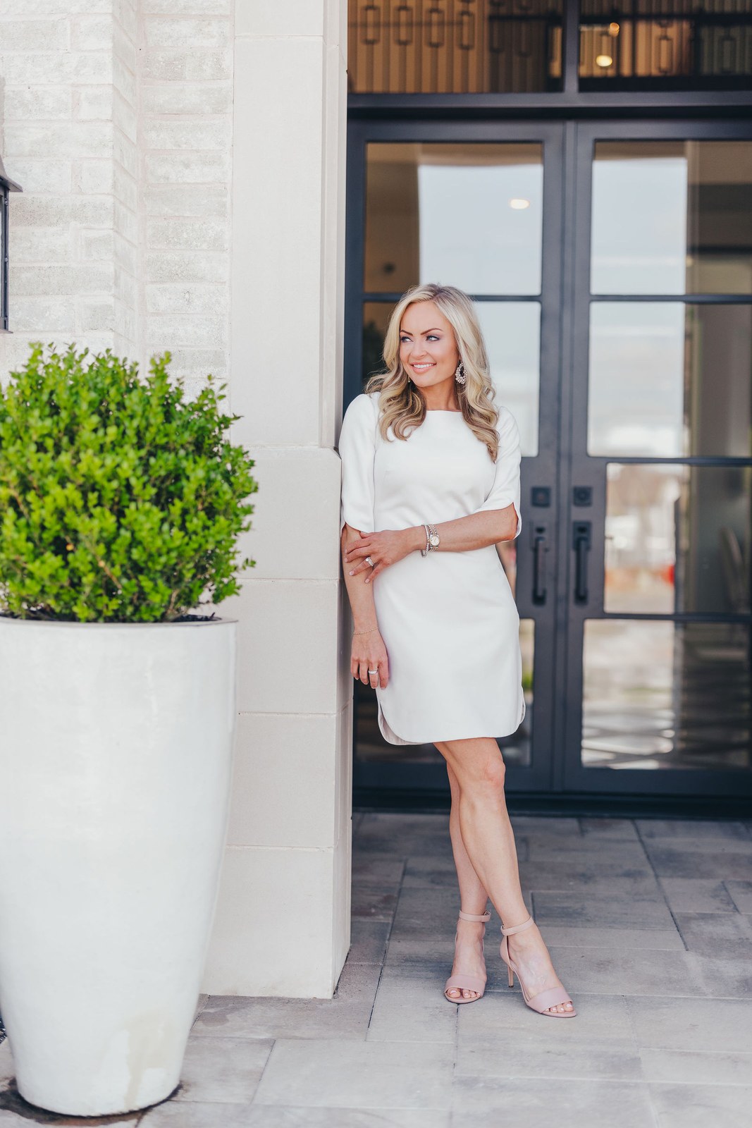 Kaitlin Lovern, North Dallas REALTOR, in a white dress striding toward a home's front door