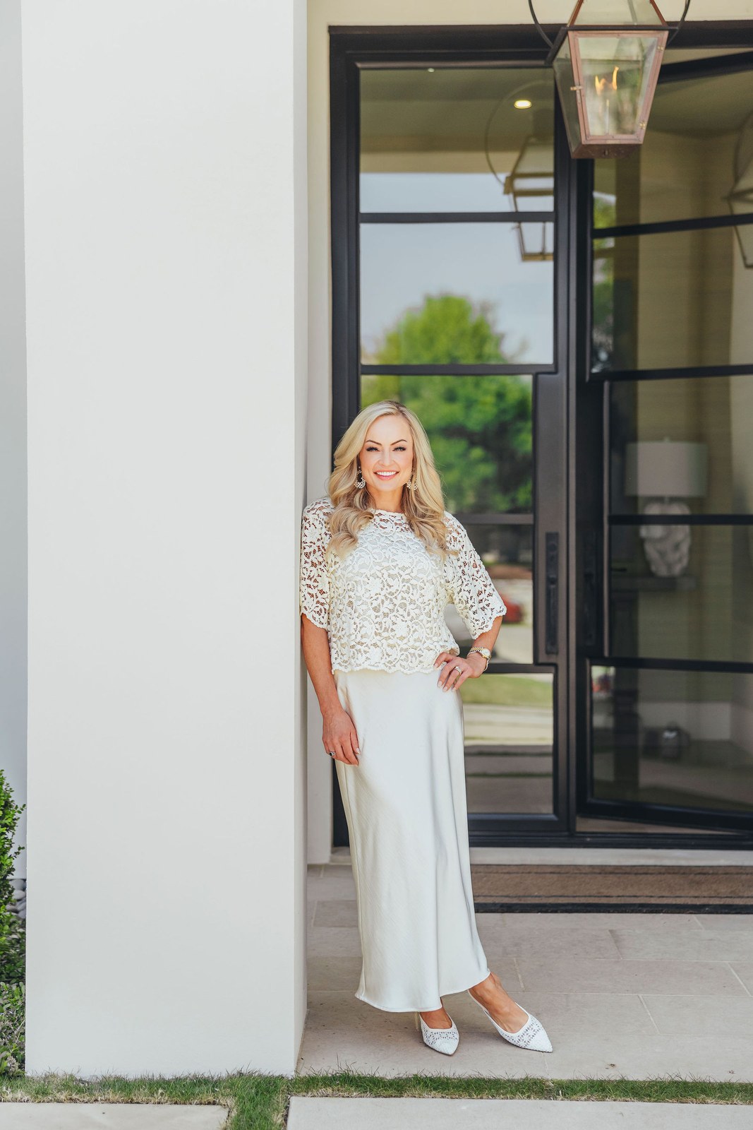 Kaitlin Lovern, North Dallas REALTOR, in white at a home entryway, serving Plano, TX